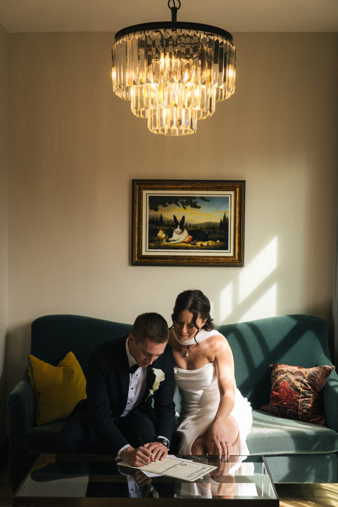 Bride and groom sign marriage license in their room at The Ramble Hotel