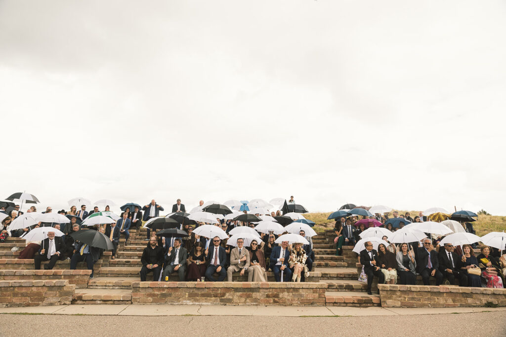 Guests sit with clear umbrellas for a Vail Mountain wedding ceremony